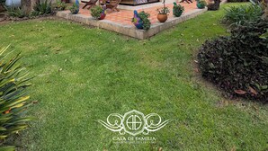 A two-story house with a balcony, a front door, and a small garden area with potted plants. - Hotel Casa de Familia de San Cristobal (San Cristóbal de las Casas)