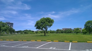 A parking lot with marked spaces, a grassy area, and buildings in the background. - Oak Garden Hotel (Hualien City)