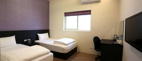 A hotel room with two beds, a desk, a chair, a TV, an air conditioner, and a window with a view.