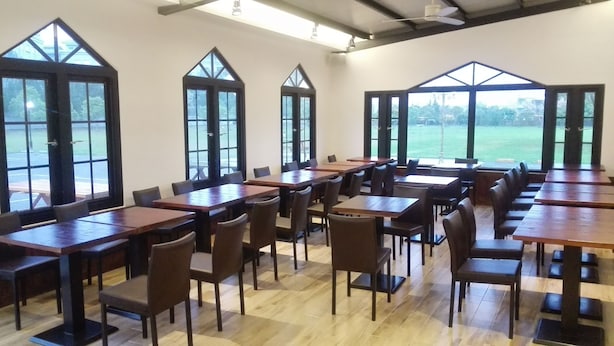 A spacious room with large windows, wooden tables, and chairs arranged for dining. - Oak Garden Hotel (Hualien City)