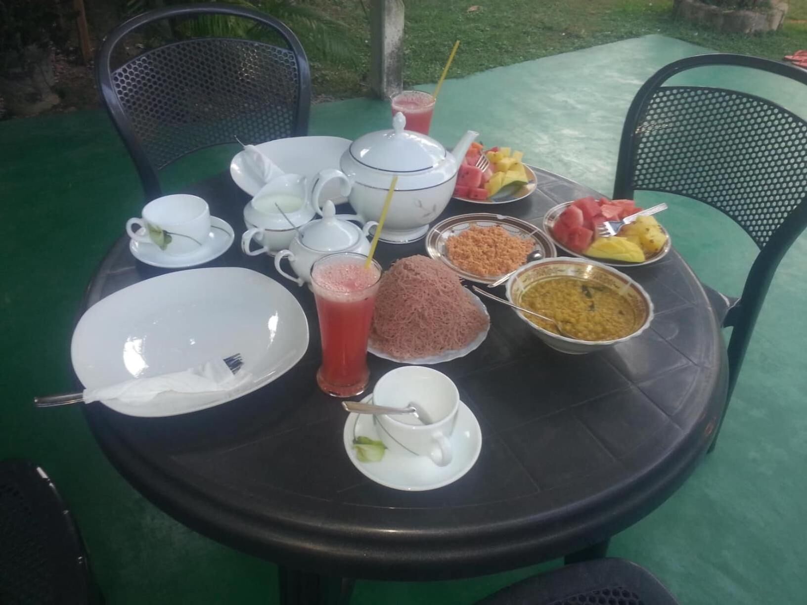 A round table with various dishes, including a fruit bowl, a bowl of lentils, and a glass of juice.