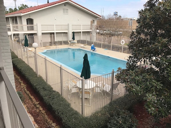 Una piscina rodeada por una valla, con un edificio al fondo.