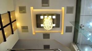Una habitación de hotel moderna con una gran lámpara de candelabro, una vitrina de vidrio y un diseño de techo único.