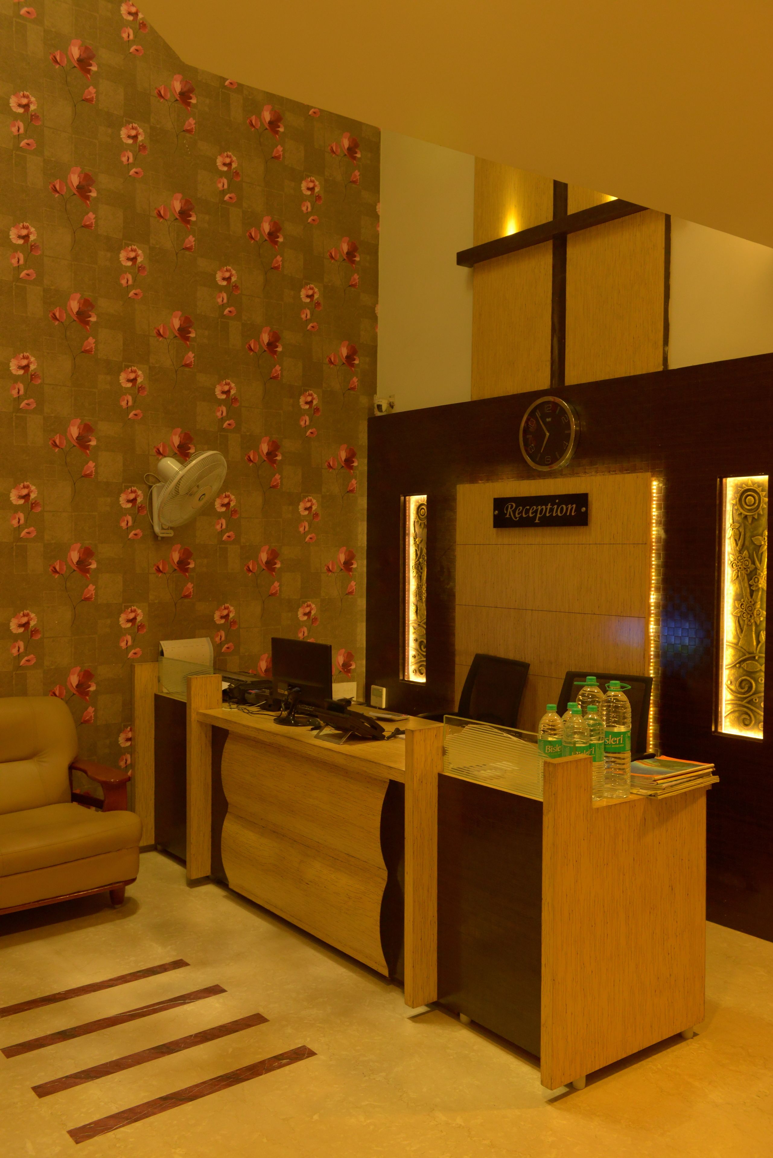 A reception desk with a clock, a sign reading "Reception," and a wall with a floral pattern.