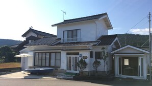 A two-story house with a traditional tiled roof, a balcony, and a small attached garage. - Heart Land Hills View of yacht harbor house (Nanao)