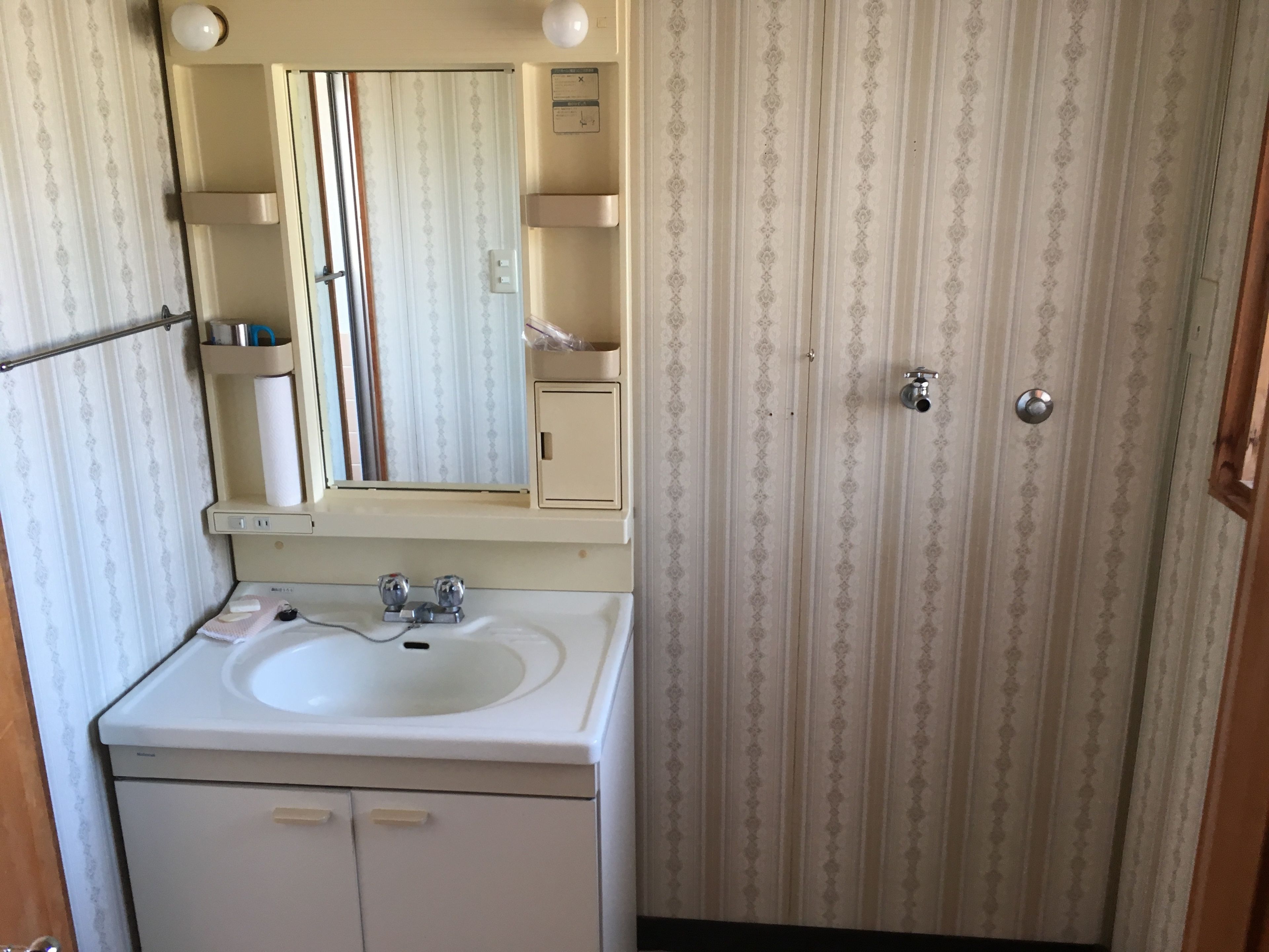 Une salle de bain avec un lavabo, un miroir et une porte à clé.