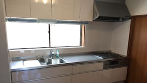 A kitchen with a stainless steel sink, a gas stove, and white cabinetry. - Heart Land Hills View of yacht harbor house (Nanao)