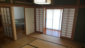 A traditional Japanese room with tatami flooring, sliding doors, and a view of a garden. - Heart Land Hills View of yacht harbor house (Nanao)