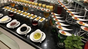 Un buffet proposant une variété de plats et de boissons, notamment des brochettes de fruits, des petites portions de nourriture et un assortiment de boissons.