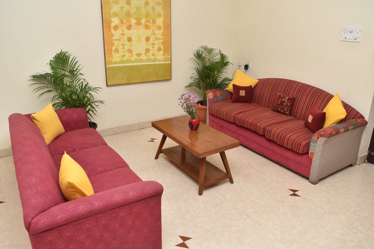 A living room with a red sofa, a wooden coffee table, and two potted plants.