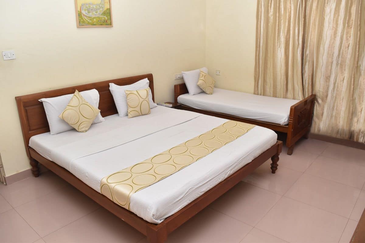 A double bed with a wooden frame and a white mattress, two pillows, and a decorative headboard.