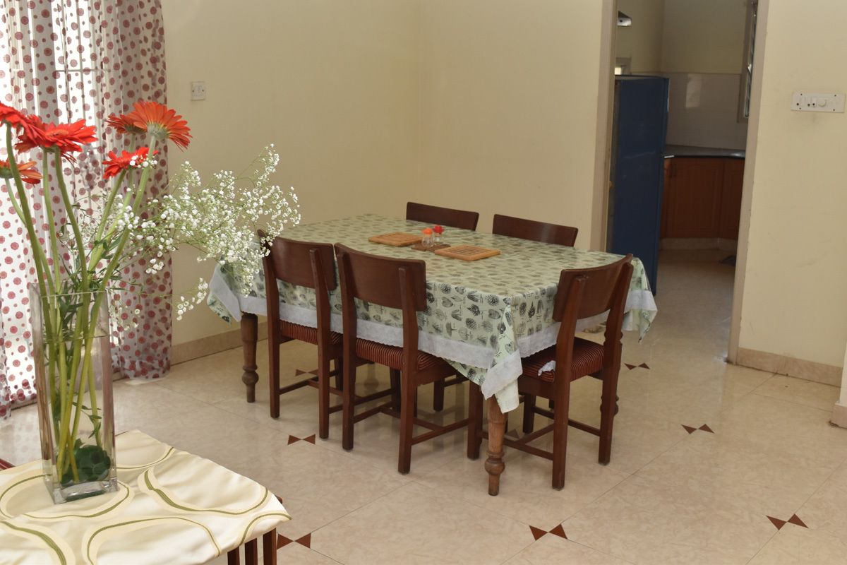 A dining area with a table set for six, surrounded by wooden chairs.