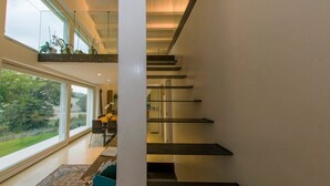 A modern interior with a staircase, large windows, and a view of greenery outside. - Hillside Villa with Swimming Pool and Jacuzzi - Frasassi Caves (Sassoferrato)