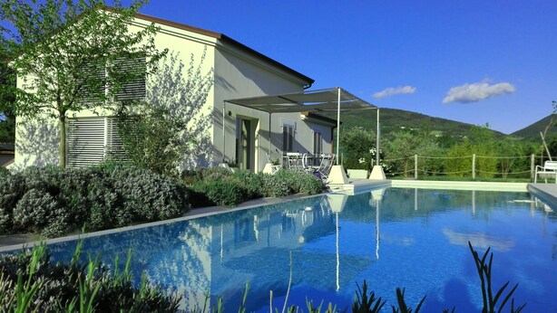 A swimming pool with a house in the background. - Hillside Villa with Swimming Pool and Jacuzzi - Frasassi Caves (Sassoferrato)