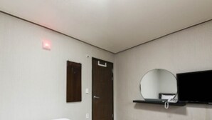 A hotel room with a bed, a door, a mirror, and a television mounted on the wall. - Namwon Hotel (Namwon)
