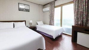 A hotel room with two beds, a nightstand, a desk, an air conditioner, and a window with curtains. - Namwon Hotel (Namwon)