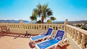 A terrace with two sun loungers, a chair, and a palm tree. - Casa del Campo - sea view villa with private pool in Moraira (Moraira)
