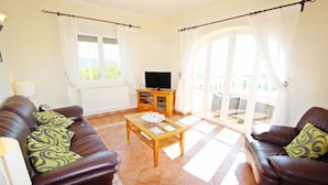 A living room with two leather sofas, a wooden coffee table, a TV stand, and a large sliding glass door leading to a balcony. - Casa del Campo - sea view villa with private pool in Moraira (Moraira)