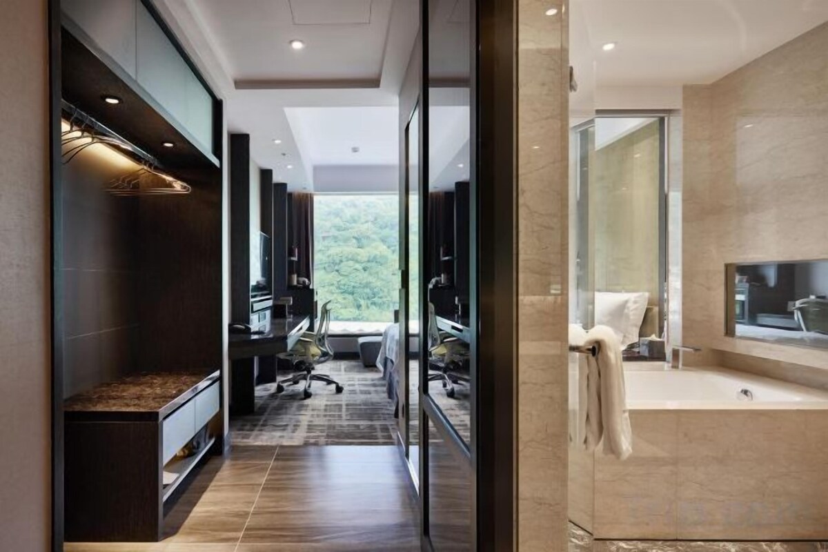 A modern bathroom with a large mirror, a bathtub, and a shower area.