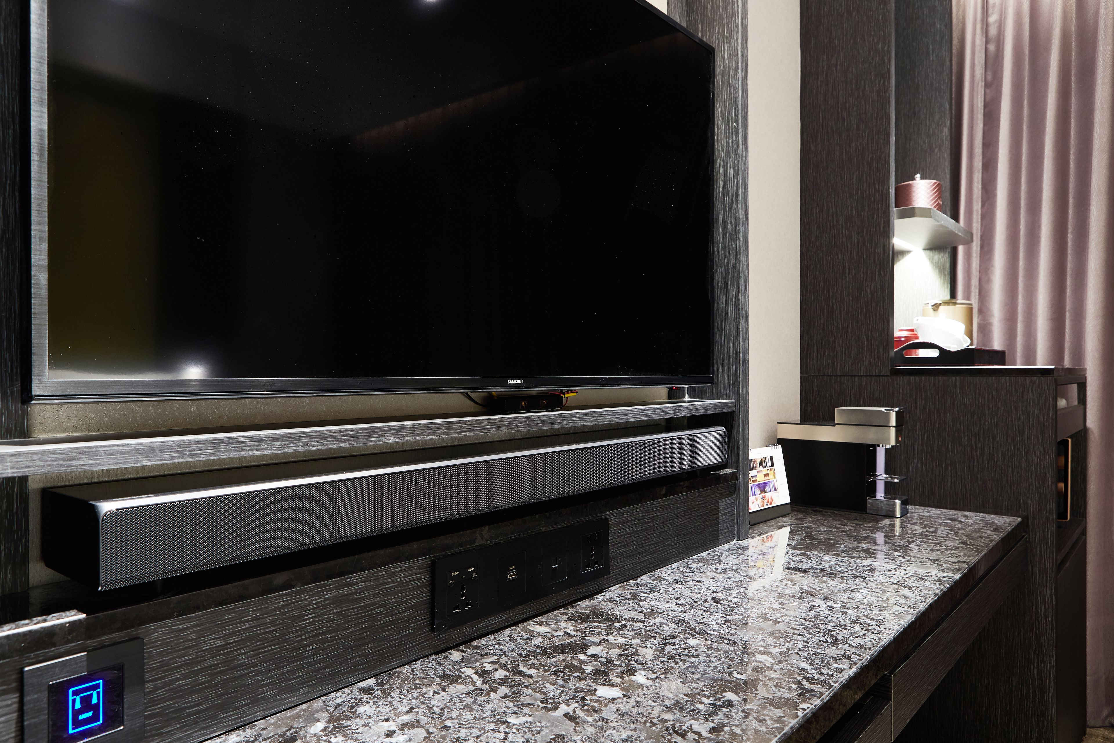 A modern entertainment unit with a large flat-screen TV, built-in speakers, and a control panel.