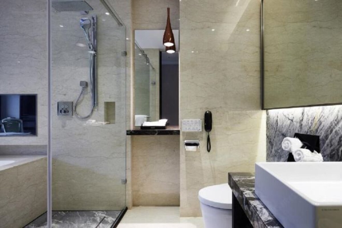 A modern bathroom with a glass-enclosed shower, a marble vanity, and a white sink.