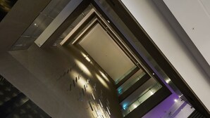 A modern interior with a high ceiling, reflective surfaces, and a central open space with lighting fixtures. - The Tango Taipei Jiantan (Taipei)
