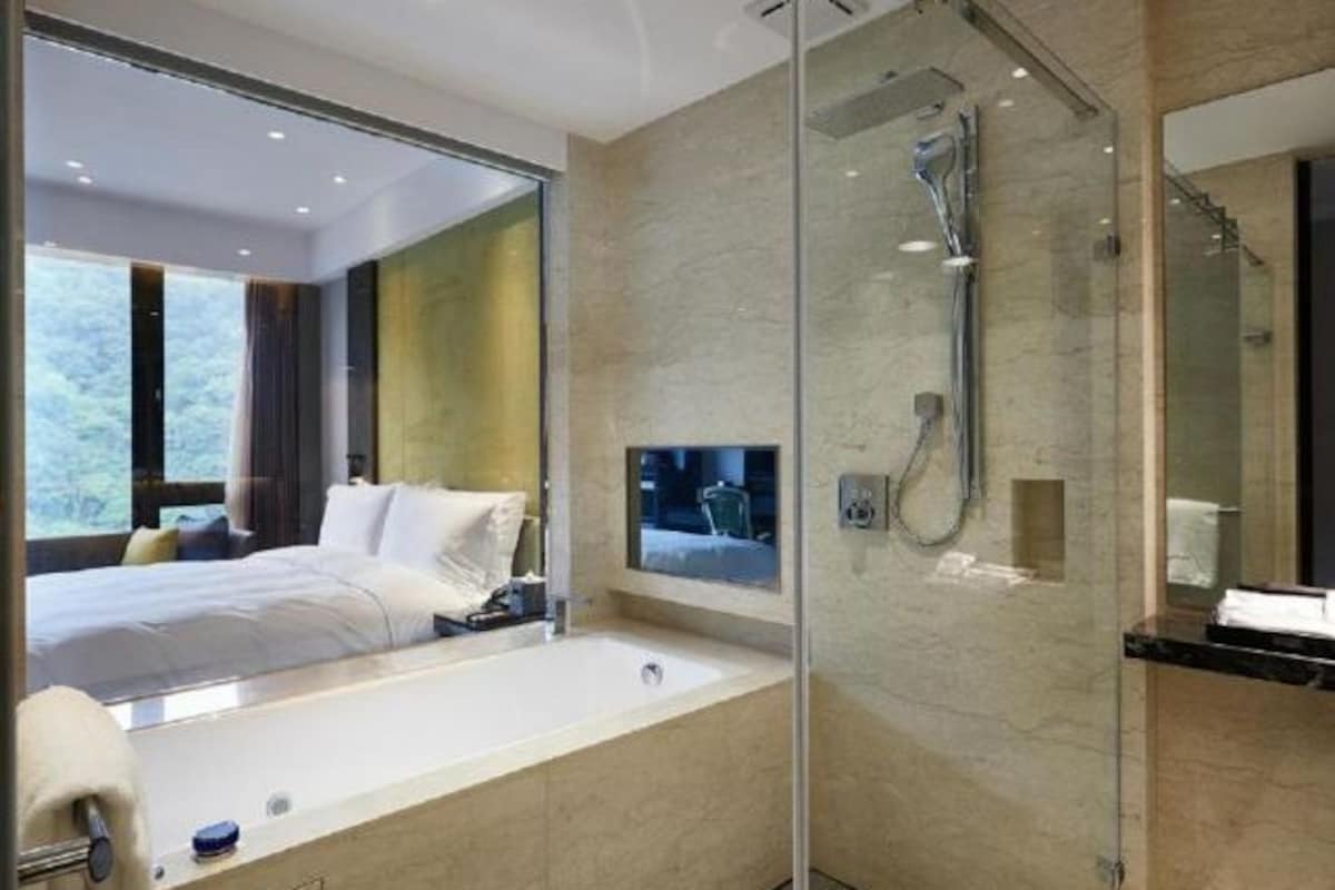 A modern bathroom with a glass-enclosed shower, a large mirror, and a bathtub.