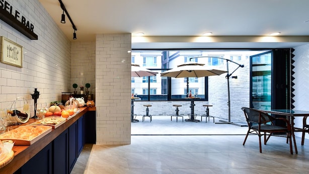 Uma área de bar moderna com um balcão comprido, várias mesas e guarda-sóis.