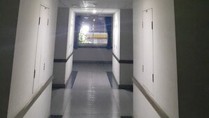 A corridor with white walls, a tiled floor, and a ceiling with recessed lighting and a smoke detector. - Phuphaya Hotel (Pak Chong)