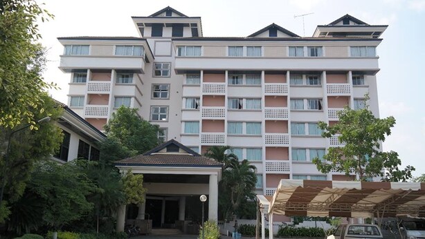 A multi-story hotel with a central entrance, a covered parking area, and a white Isuzu truck parked in front. - Phuphaya Hotel (Pak Chong)