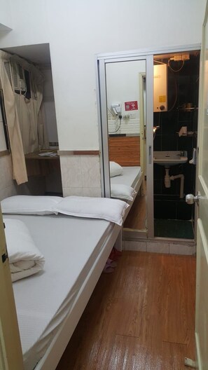 A room with two beds, a bathroom with a sink, and a door leading to another room. - Pandora Inn (Kowloon)