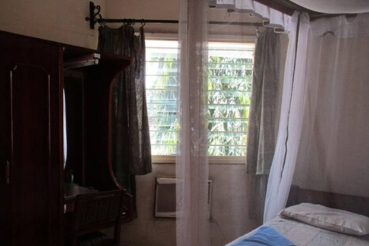 Una habitación con una cama, un armario de madera y una ventana con vistas a la vegetación.