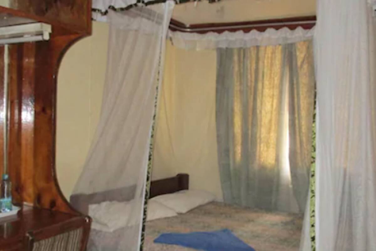 Una habitación con una cama, un armario de madera y una ventana con cortinas.