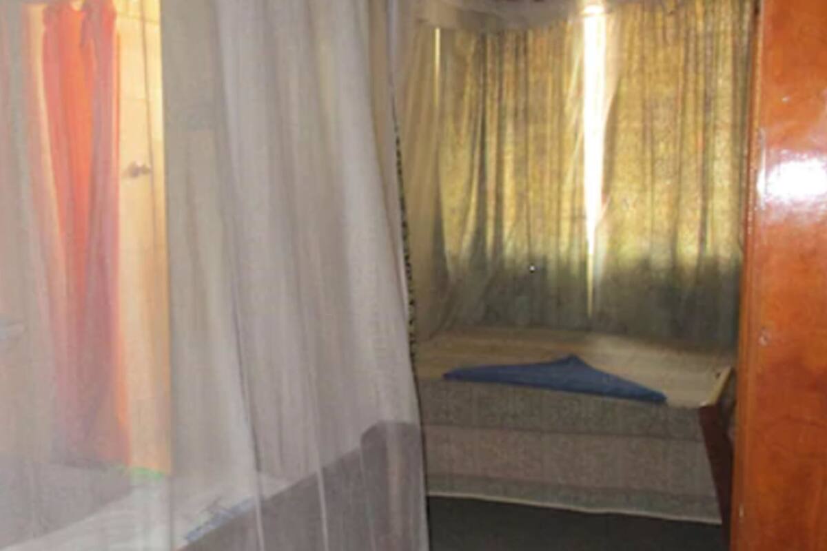 Una habitación con una cama, una ventana con cortinas y una puerta.