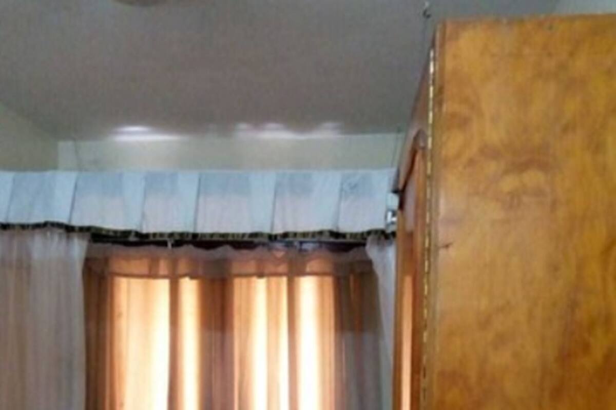 Un dormitorio con cama, una silla y un armario de madera.