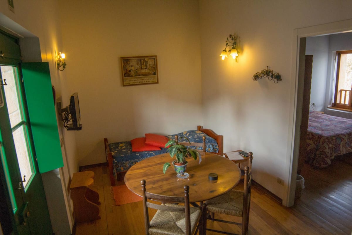 A cozy room with a wooden dining table, a sofa with floral upholstery, and a painting on the wall.