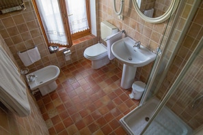 A bathroom with a toilet, bidet, sink, and shower.