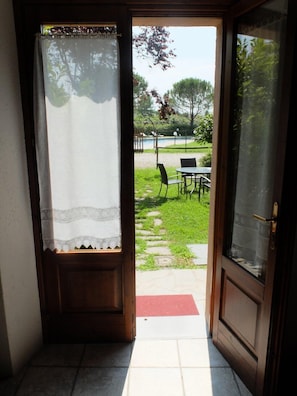 A doorway leading to an outdoor area with a table and chairs, a red mat, and a grassy lawn.