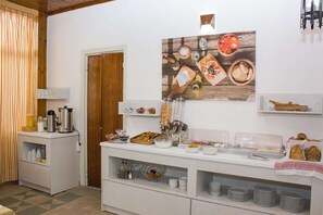 A breakfast buffet with various food items and beverages, a coffee machine, and a decorative wall piece. - Zorbas Beach Hotel (Hersonissos)