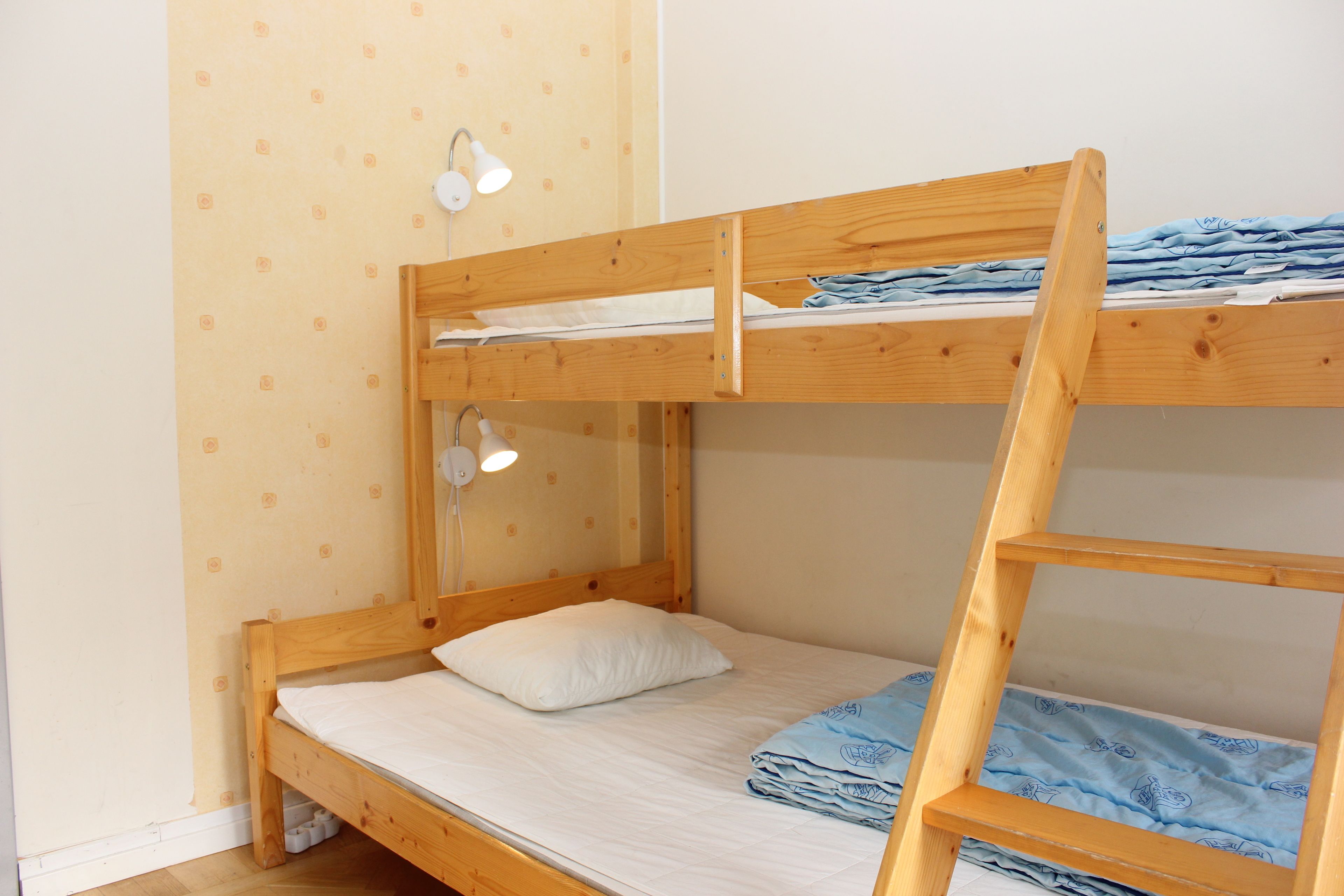 Un lit superposé avec un lit en bas, un oreiller blanc et une couverture bleue sur le lit du haut.