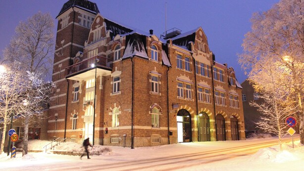 Een groot gebouw van baksteen met veel ramen en een opvallende toren.
