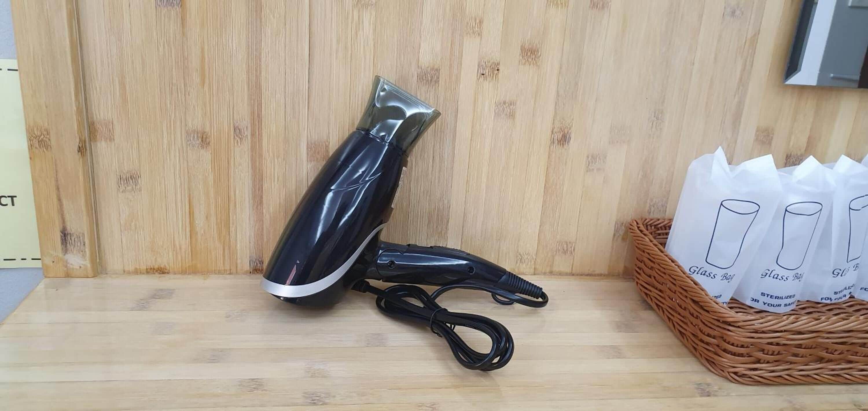 A black vacuum cleaner on a wooden floor next to a wicker basket with glass ball bags.