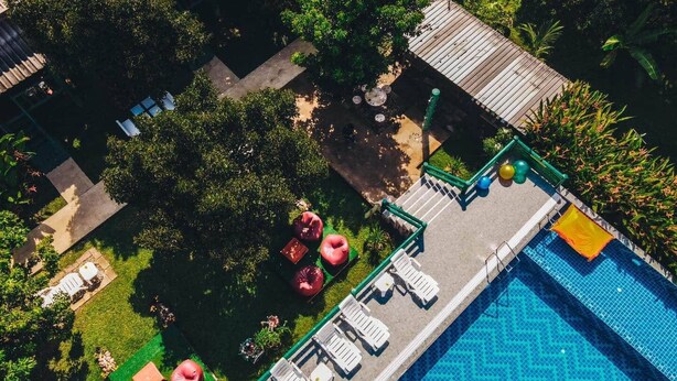 Luchtbeeld van een resort met een zwembad, ligstoelen en een tuin.