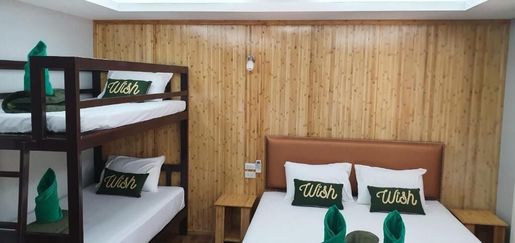 A room with bunk beds and a single bed, both with 'Wish' pillows.