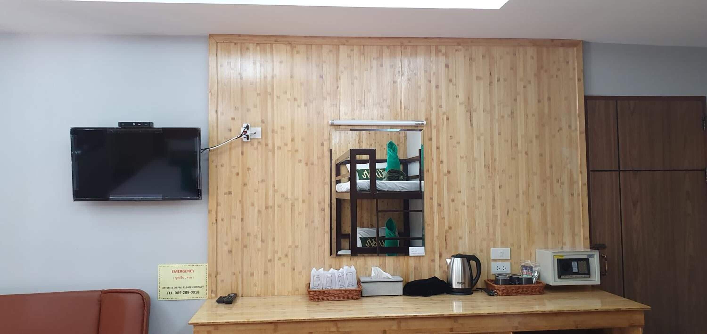 A reception area with a wooden cabinet, a television mounted on the wall, a counter with a kettle, a microwave, and a basket of tissues.