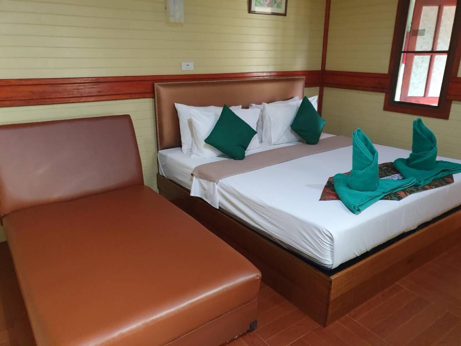 Una habitación de hotel con cama, un sofá de cuero marrón y una ventana con vistas.