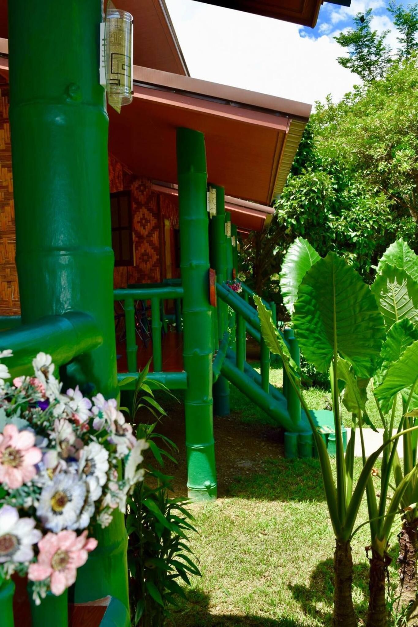 A covered outdoor area with green pillars, a wooden deck, and a grassy lawn.