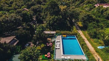An aerial view of a property with a swimming pool, lounge chairs, and a garden area.