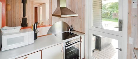 A compact kitchen with a microwave, stove, oven, and a large window.
