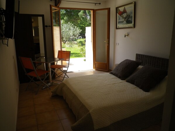 Un dormitorio con una cama, una silla, una mesita y una puerta que da a un balcón.